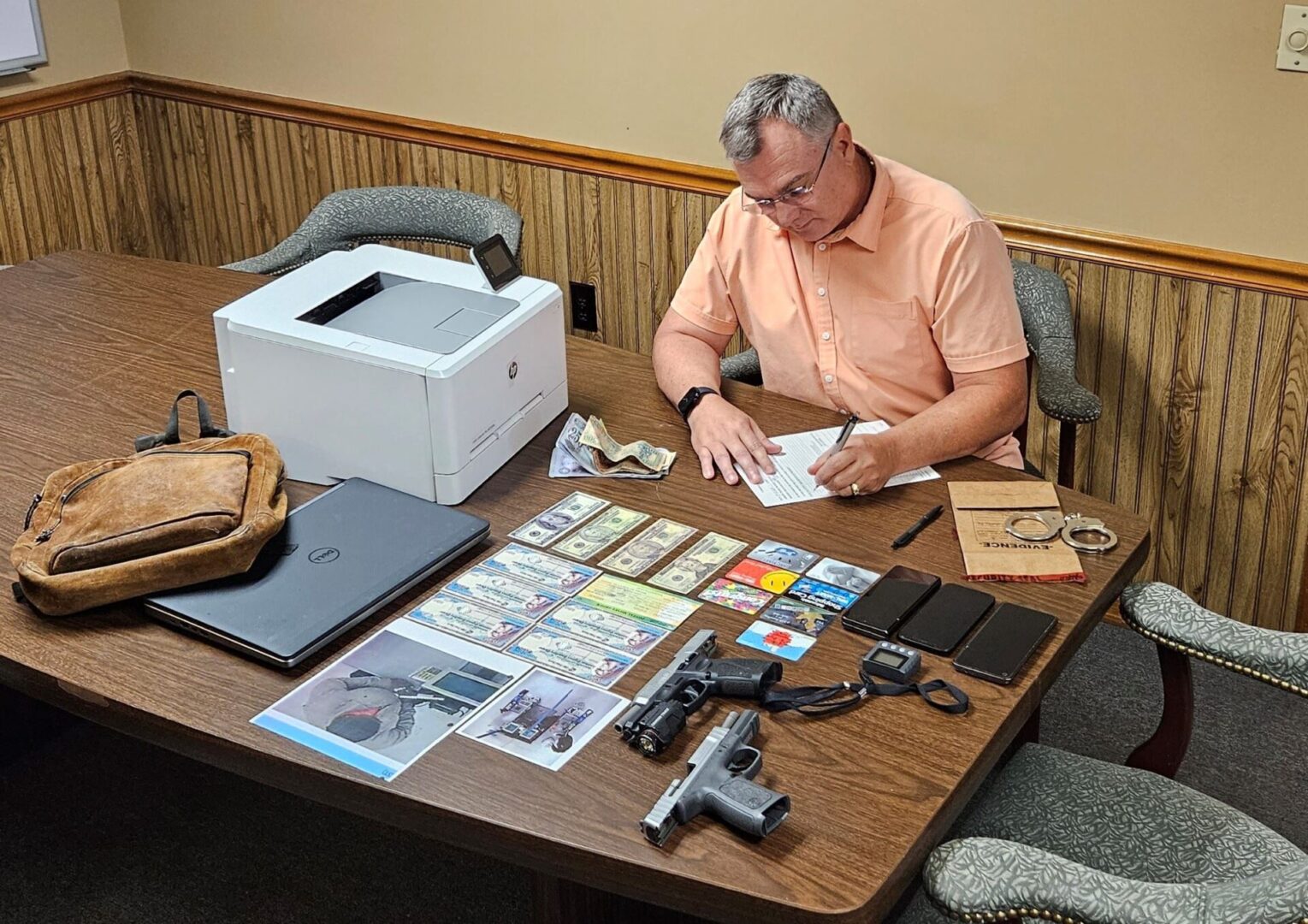 A man sitting at a table with papers and a gun.