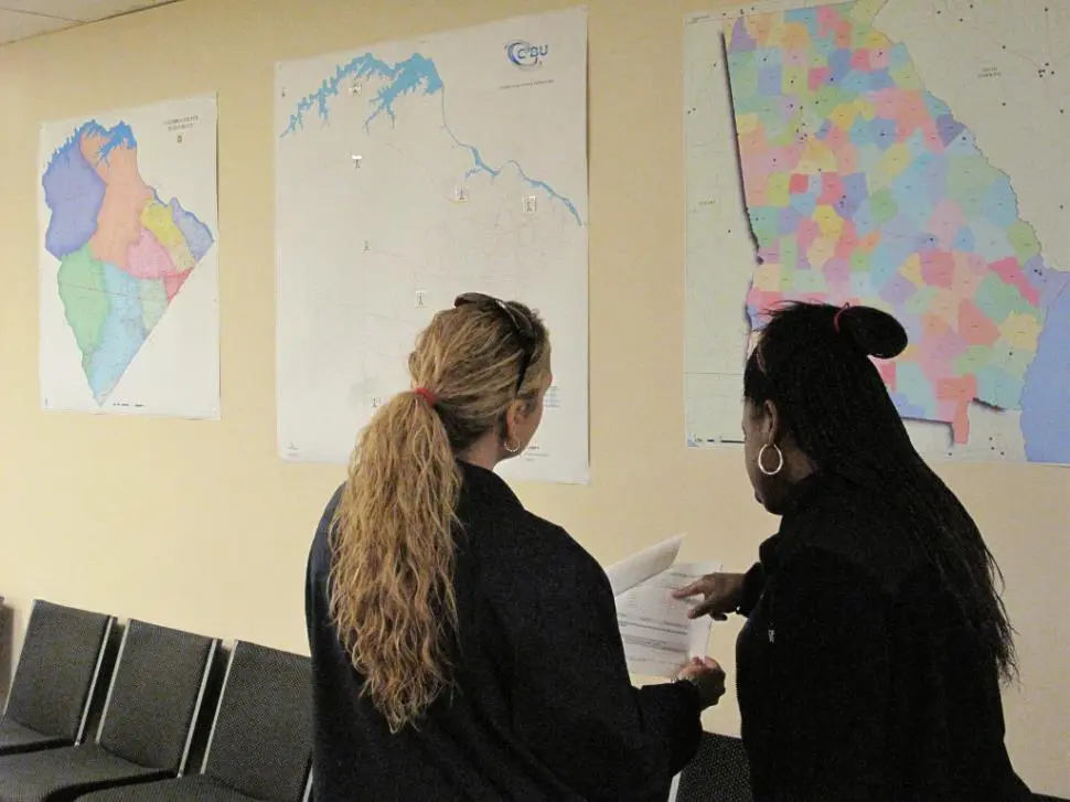 Two people standing in front of a wall with maps on it.