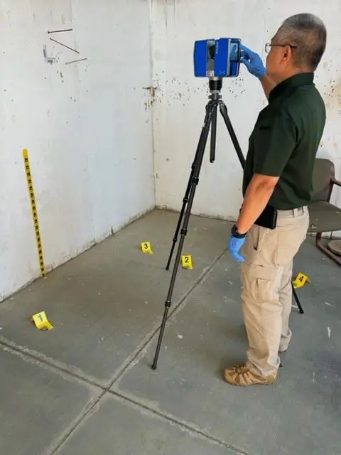 A man in green shirt using a camera on tripod.